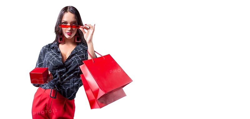 Beautiful sexy girl in glasses posing in the studio with red packages and a box for jewelry. White background. Shopping concept.