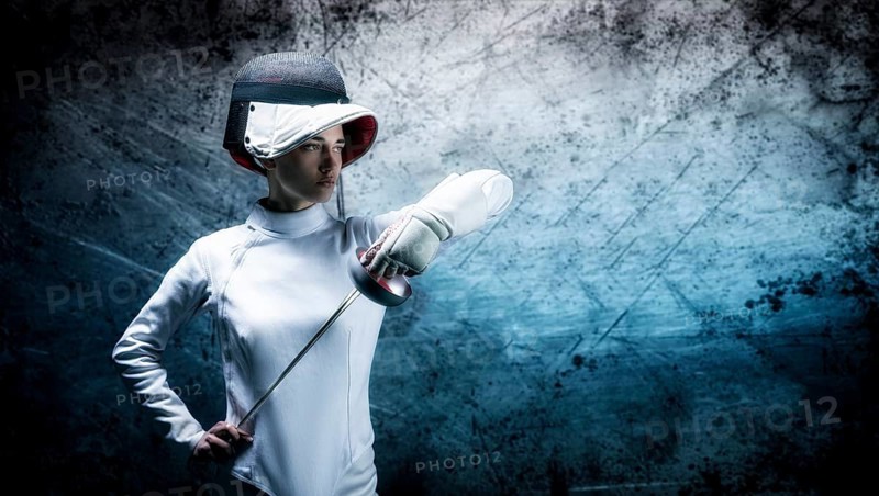 Charming girl dressed as a fencer posing with a mask and a sword. The concept of fencing.