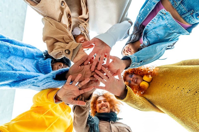 Low angle view of group of diverse young people join hands in circle