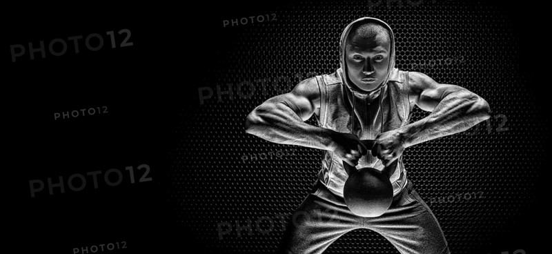 Portrait of an athlete pulling a kettlebell to his chin. The concept of sport and healthy lifestyle.