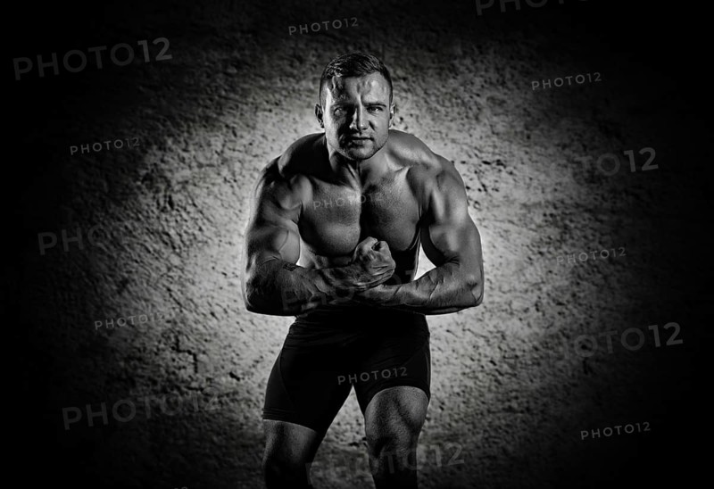 The weightlifter is posing in front of the camera