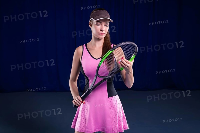 Portrait of a beautiful tennis player in a pink dress on the court. Sports concept.