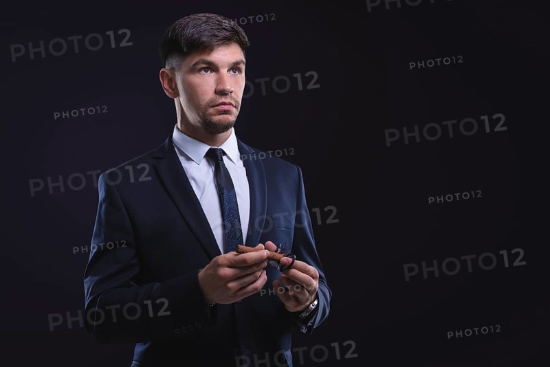 Portrait of a stylish man in a suit with a cigar. Business concept.
