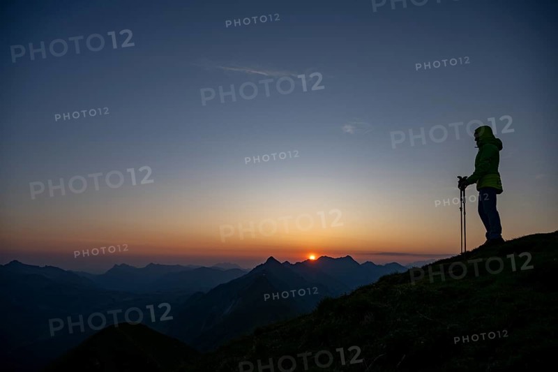 Mountaineer on mountain ridge with Rothorn peak in the background at sunrise