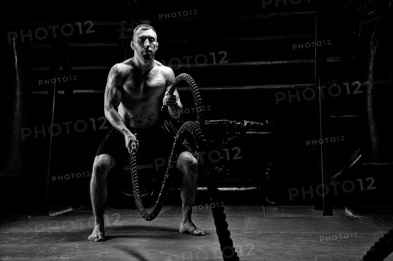 The athlete works with crossfit ropes in the gym. The concept of sports