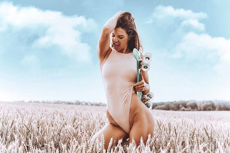 Image of a sexy girl in a bodysuit with a skateboard. Sports concept.
