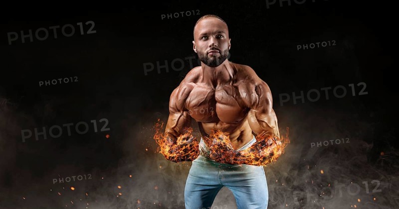 Isolated athlete on a background of smoke with burning hands. Fat burning concept. Bodybuilding.