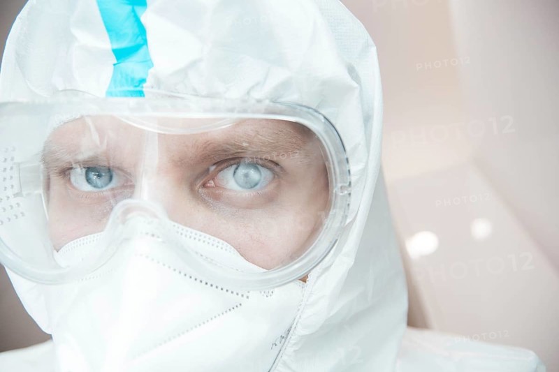 Medical laboratory assistant in a chemical protection suit and safety glasses