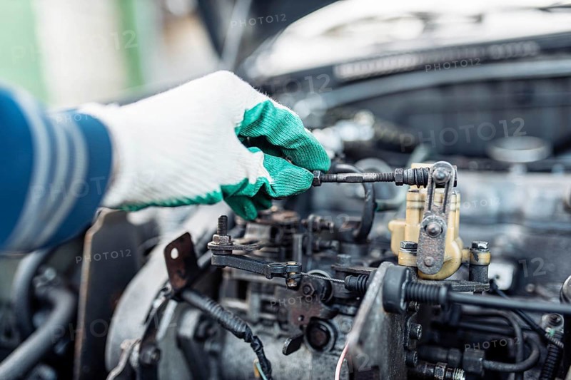 Auto mechanic regulates fuel supply with throttle cable lever