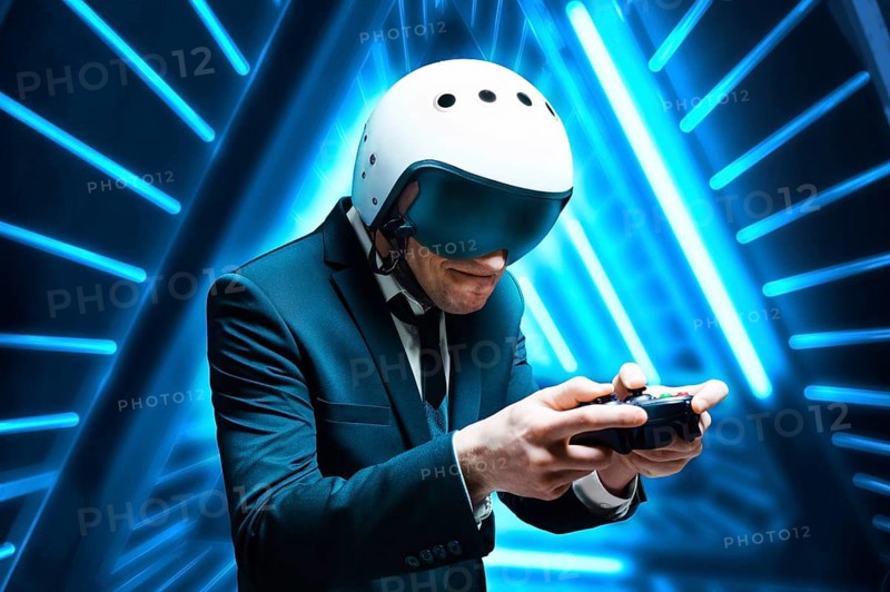 Portrait of a man in a suit and helmet of a pilot with a joystick in his hands. He enthusiastically plays a computer game. Game space. Game concept.