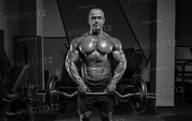 Professional weightlifter posing in the gym with a barbell in his hands. Classic bodybuilding.