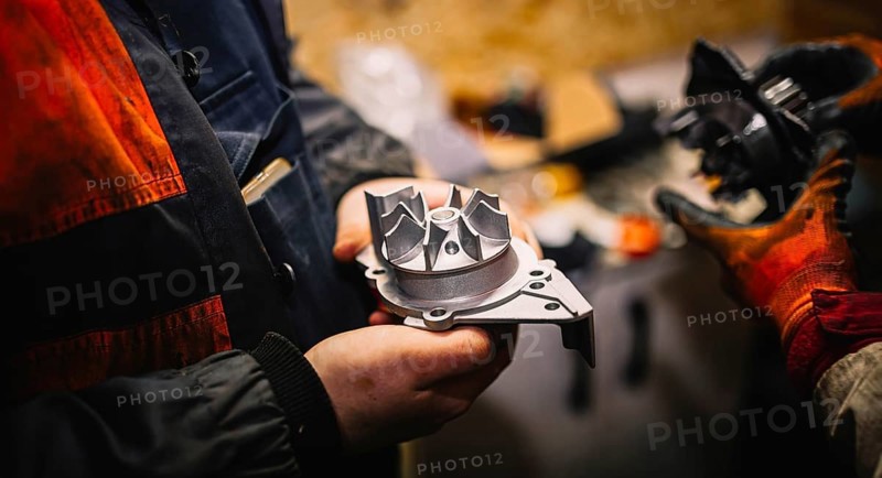 Automotive water pump of the engine cooling system in the hands of an auto mechanic