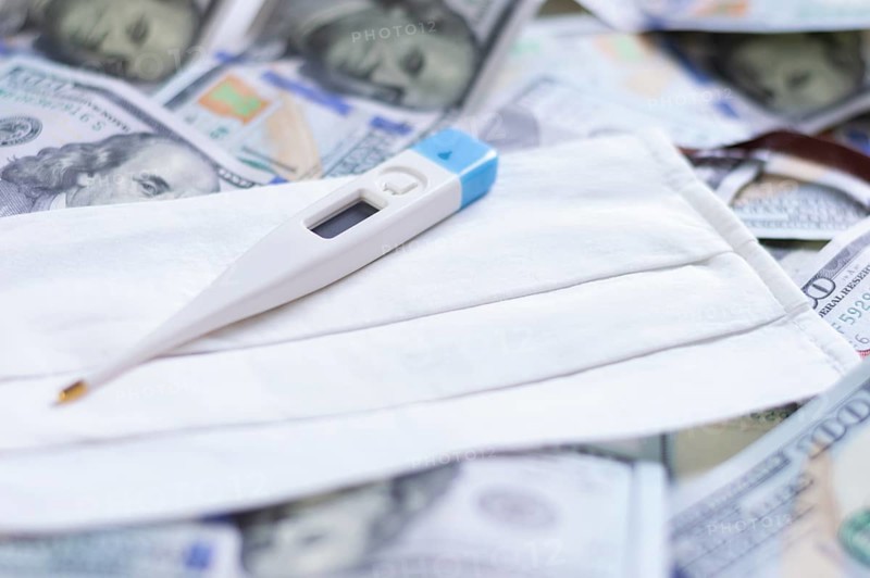 Medical mask and a thermometer lie on one hundred dollar bills. The concept of an epidemic
