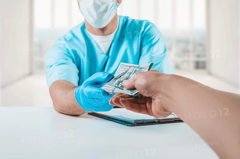 The doctor in the office takes a bribe from the patient. The concept of corruption in medicine.