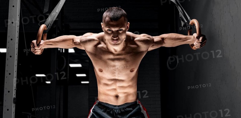 The athlete pulls himself up on the gymnastic rings. The concept of sport and healthy lifestyle.