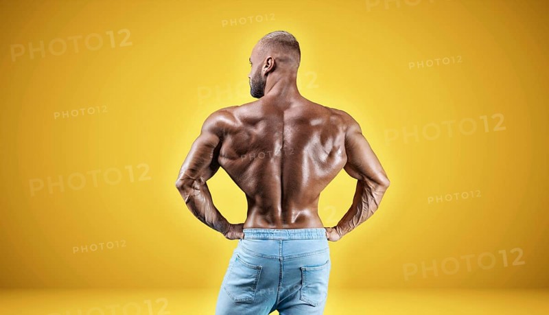 Isolated professional sportsman on a yellow background. Bodybuilding concept. Panorama. Advertising of a gym and sports nutrition.