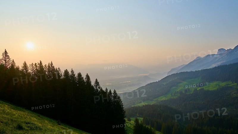 Sunrise over a misty mountain landscape with forest in the foreground