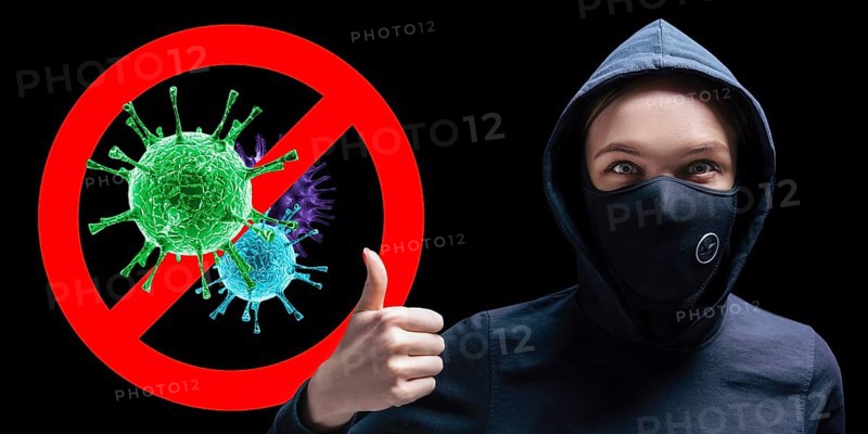 Portrait of a girl in a protective mask who shows up her finger against the background of the stop viruses sign.