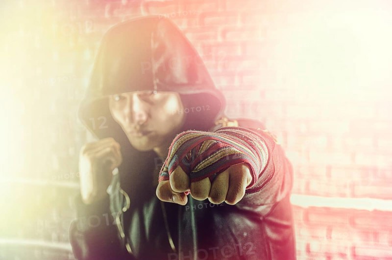 Boxer in a black sweatshirt and bandages wound on his hands beats his fist forward. The concept of sports