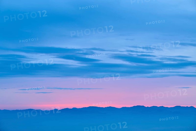 Dawn with pink and blue colours over a mountainous silhouette