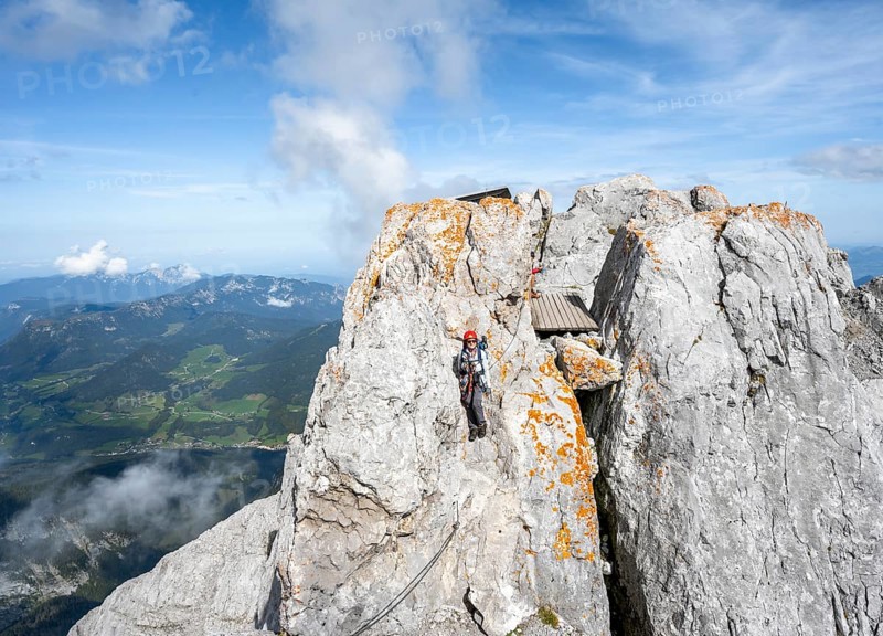 Female mountaineer climbing a via ferrata secured with a steel cable