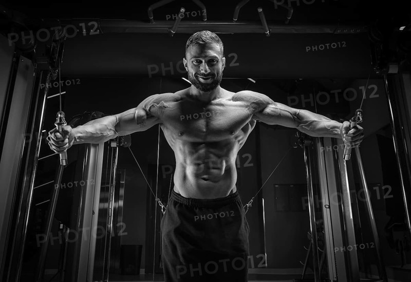 Muscular athlete training in a crossover at the gym. Pumping the torso. Fitness and bodybuilding concept.