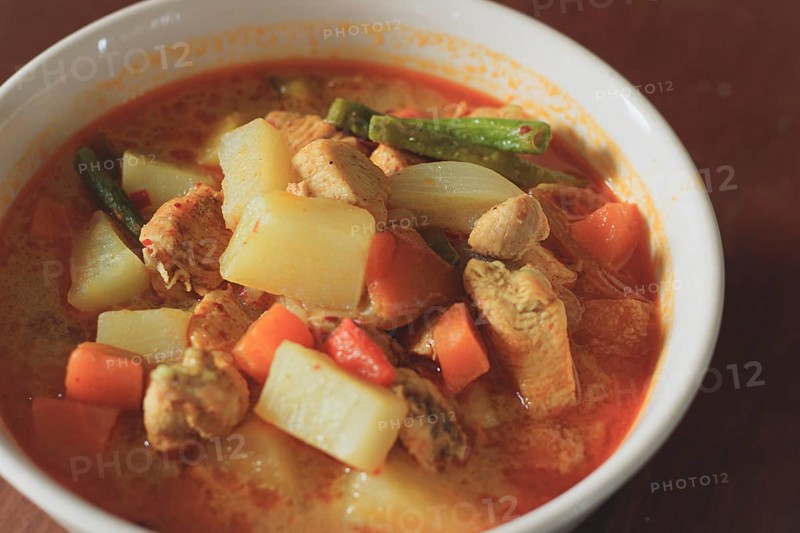 A bowl of hearty chicken curry with potatoes and carrots