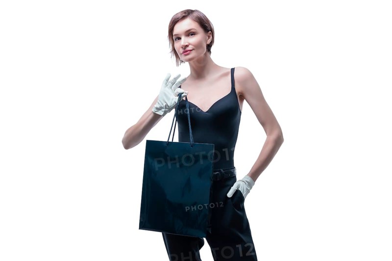 Stylish tall girl in white gloves demonstrates a black luxury package. The concept of safe shopping during a pandemic