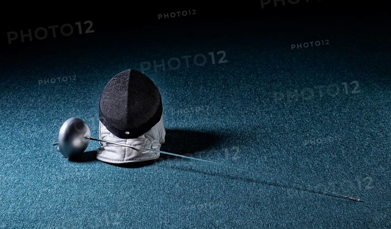 The sword and mask lie on a blue background. The concept of fencing.