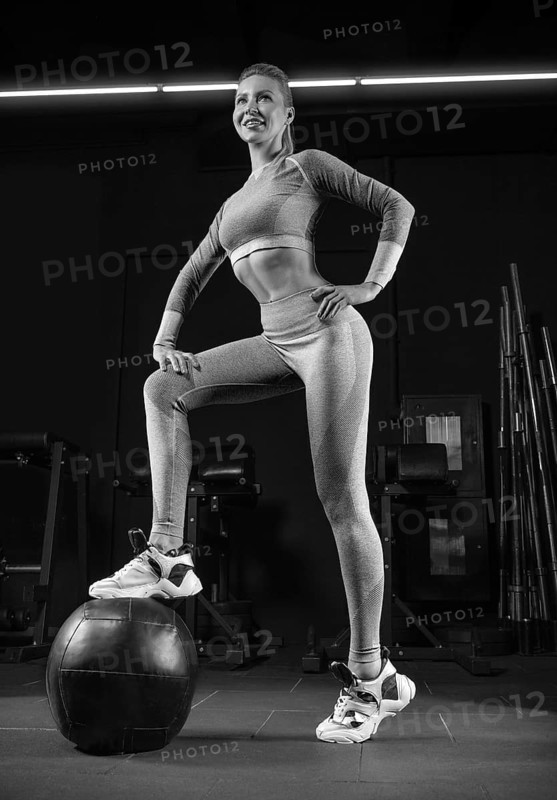 Charming blonde posing in the gym with a fitness ball. Front view. The concept of sports
