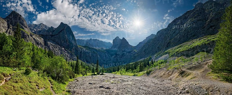 Panorama of a mountain landscape with the sun shining over the peaks