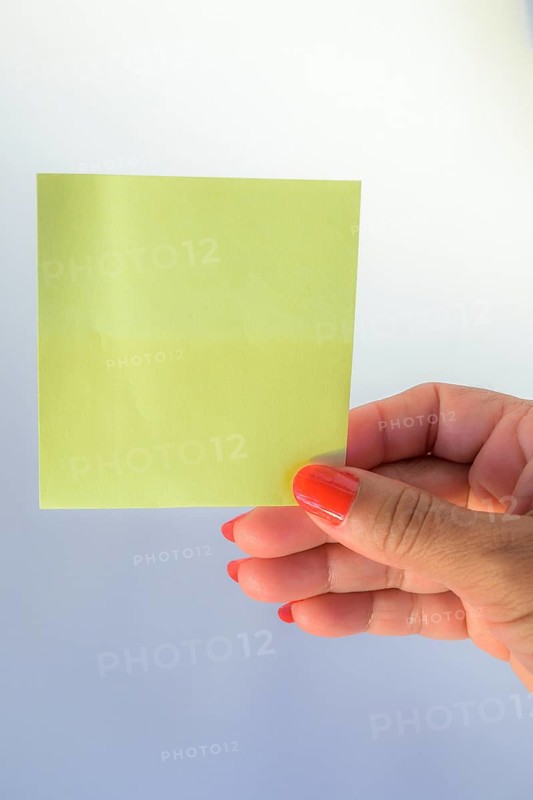 Woman's hand with painted nails holding blank letter paper on pure white background