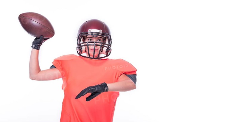 Woman in the uniform of an American football team player throws the ball. Sports concept.