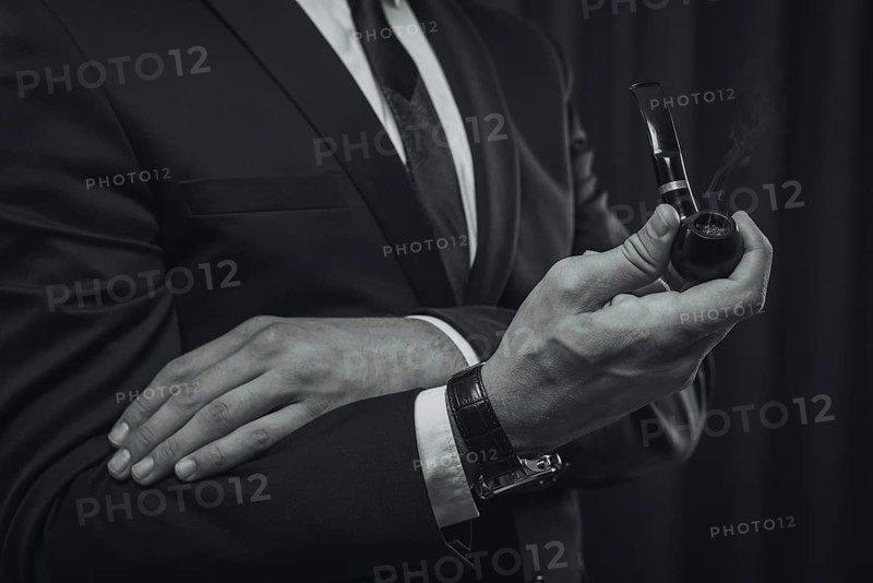 Image of male hands holding a smoking pipe. Tobacco smoking concept.