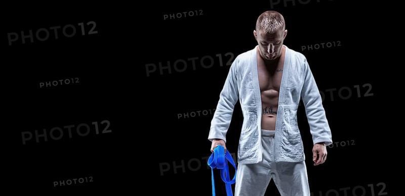 Professional athlete stands in the gym in a kimono with a blue belt. Concept of karate