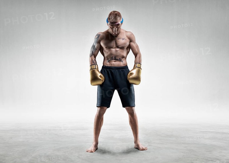 Professional wrestler is standing in a bright room. Mixed martial arts