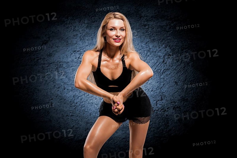 Sportive girl with an ideal figure posing in the studio with dumbbells in her hands.