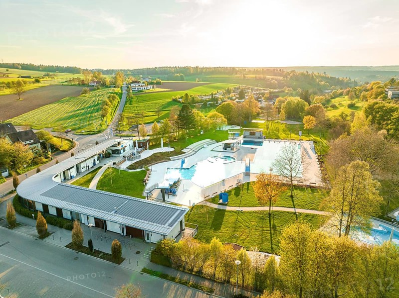 Wide-angle drone shot of an outdoor swimming pool in a rural area during sunset