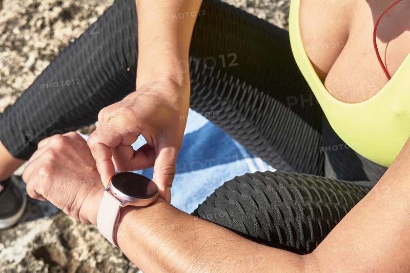 Close-up of a person checking a smartwatch while wearing sportswear during an outdoor workout