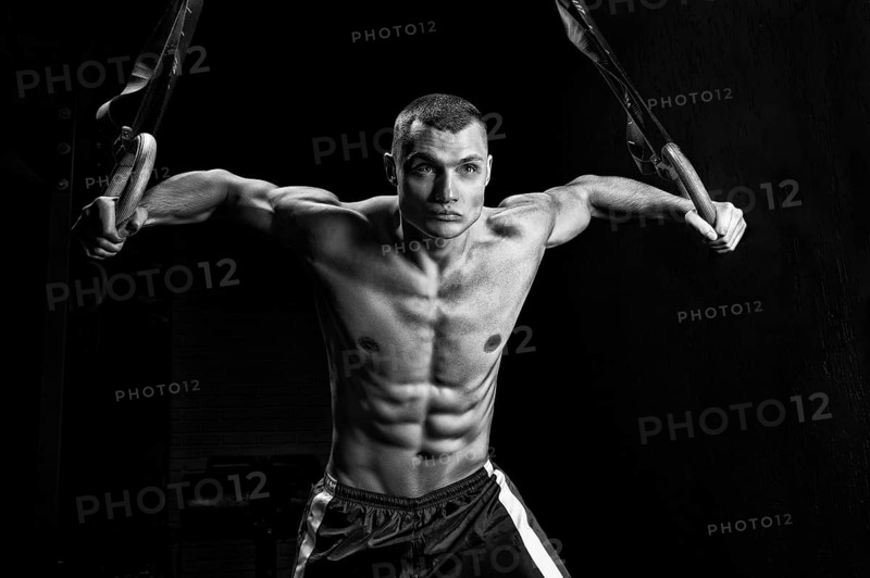 The athlete pulls himself up on the gymnastic rings. The concept of sport and healthy lifestyle.