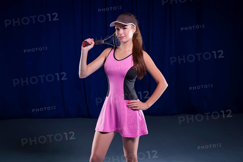 Portrait of a beautiful tennis player in a pink dress on the court. Sports concept.