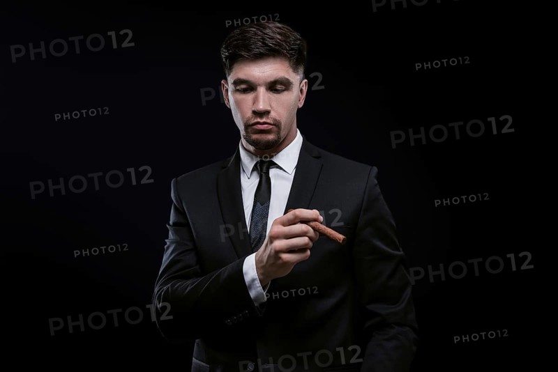 Portrait of a stylish man in a suit with a cigar. Business concept.