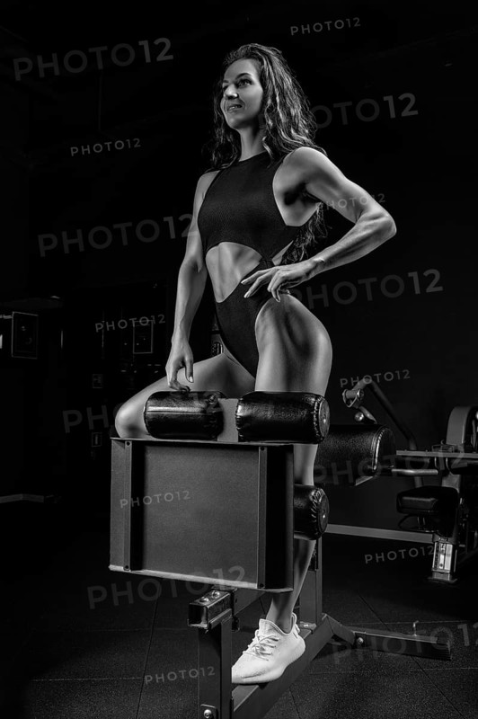 Adorable brunette poses in training apparatus in the gym. Fitness and bodybuilding concept.