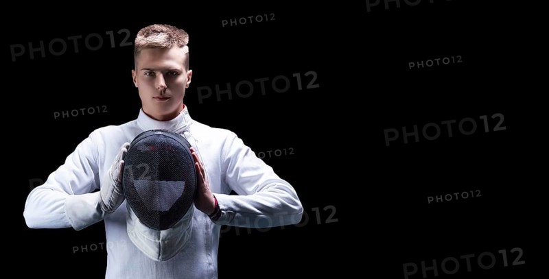 Portrait of a male fencer on a black background. He holds a helmet in front of him. The concept of fencing.