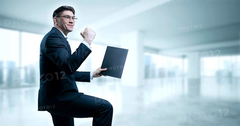 Man with a tablet in his hand screams with joy in the office. The concept of achieving success in business.