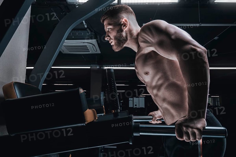 Portrait of an athlete doing push-ups on the uneven bars in the gym. Bodybuilding and fitness concept.
