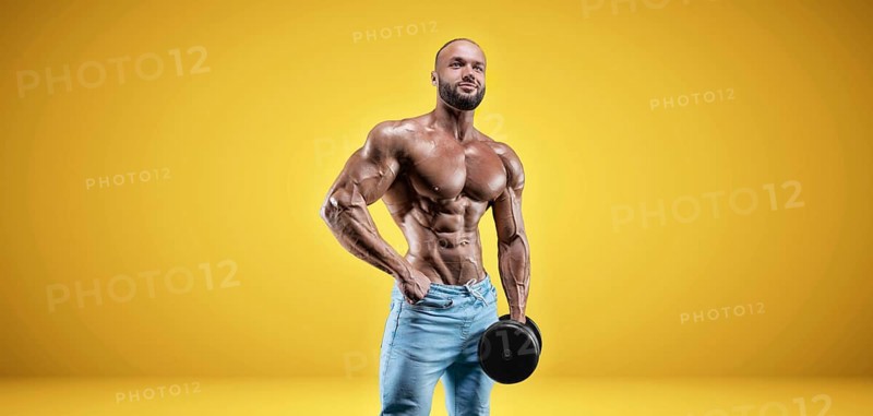 Isolated professional sportsman on a yellow background. Bodybuilding concept. Panorama. Advertising of a gym and sports nutrition.