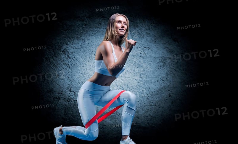 Charming girl does an exercise called lunges. Elastic band for training. The concept of fitness
