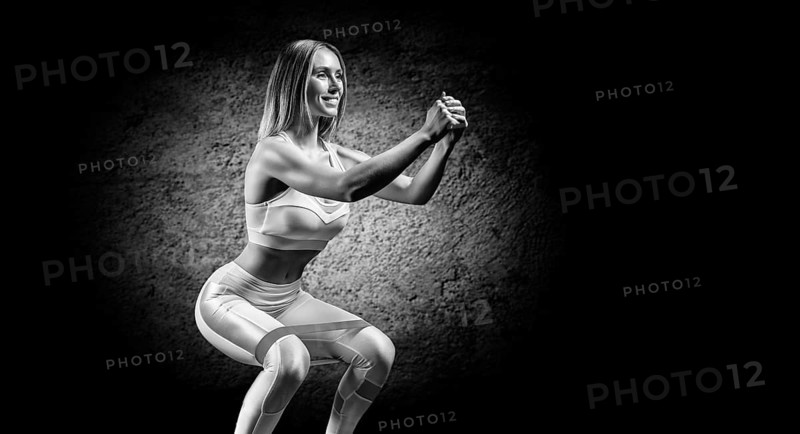 Charming girl is training in the gym with a rubber band. The concept of bodybuilding