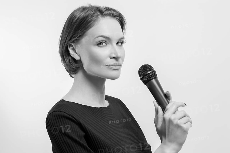 Portrait of an elegant stylish woman with a microphone. White background. Karaoke concept.